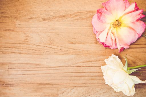 A top view closeup of a cosmos flower and a white rose on a wooden table