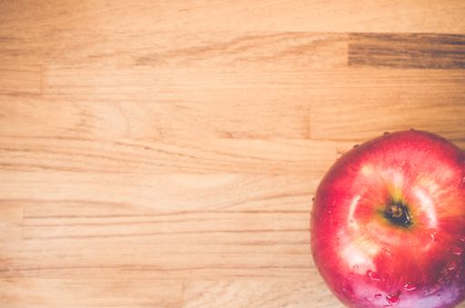 A top view of a delicious and fresh red apple on a wooden surface
