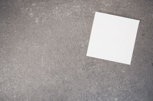 A top view of a blank paper memo on a rough-textured surface with copy space