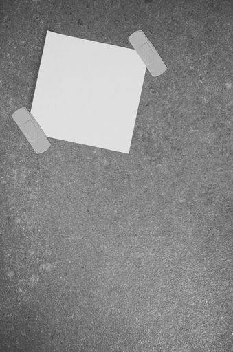 A top view closeup of a white memo paper on a toned rough stone textured surface