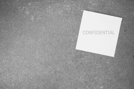A top view of a blank paper memo with "CONFIDENTIAL" text on a rough-textured surface with copy space