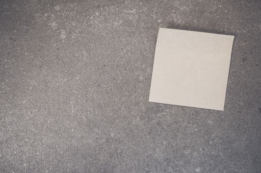 A top view of a blank paper memo on a rough-textured surface with copy space