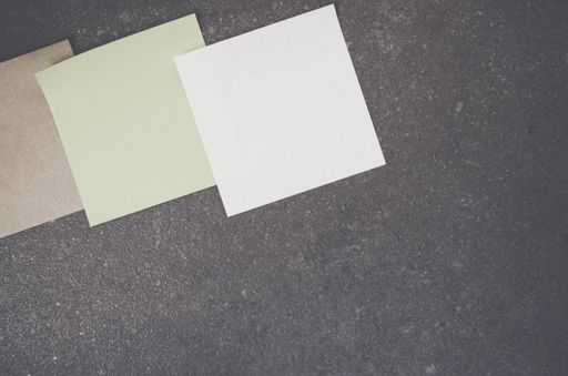 A top view closeup of colorful memo papers on a toned rough stone textured surface