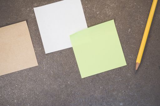 A top view of blank paper memos with pencil on a rough-textured surface with copy space