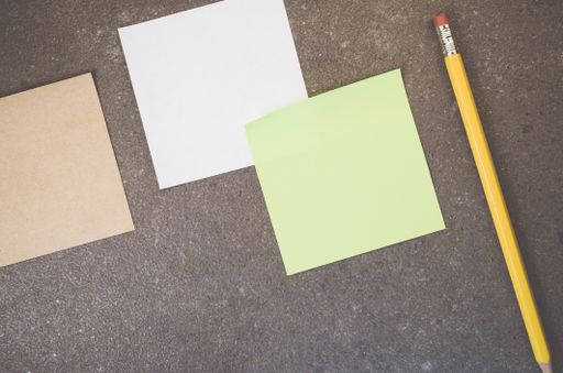 A top view of blank paper memos with pencil on a rough-textured surface with copy space