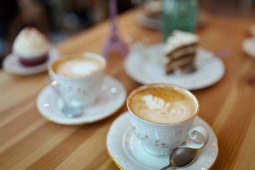 A selective focus shot of two cups of cappuccino coffee with foam on a wooden table