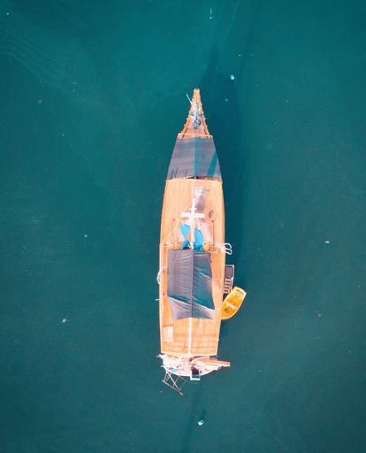 A vertical aerial overhead shot of a boat at the sea