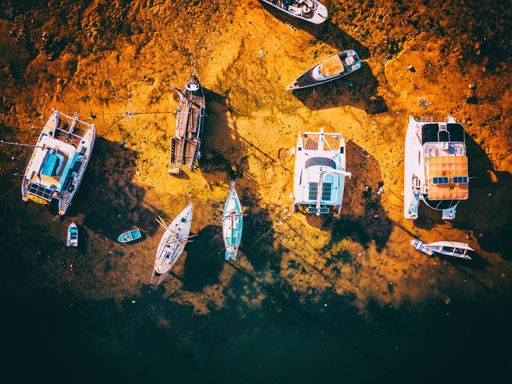 An aerial overhead shot of boats at the sea coast