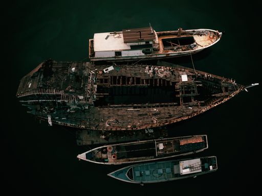 An aerial overhead shot of abandoned boats at the sea