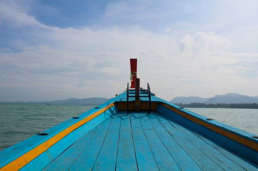 A beautiful view of the blue and yellow boat and the ocean with the mountains in the background