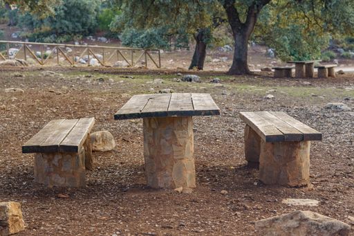 wood and stone table in a public park in the mountains with holm oaks in the background