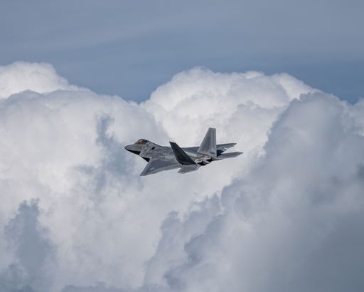 The F-22 Raptor in mid-flight against a clouded sky