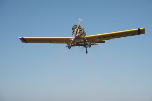 A single-engine propeller airplane flying in a perfectly clear blue sky