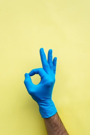 A vertical shot of a hand in a surgical glove showing the OK sign