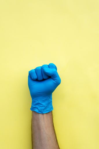 A vertical shot of a hand in a surgical glove showing a fist