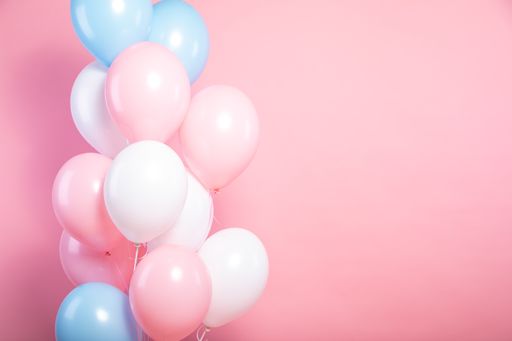 A closeup of pink and blue balloons in front of a pink background