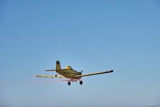 A single-engine propeller airplane flying in a perfectly clear blue sky
