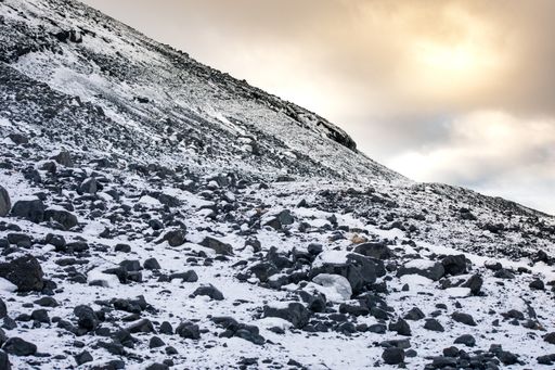 The rocky landscape of the snowy mountains under a cloudy sky during daytime