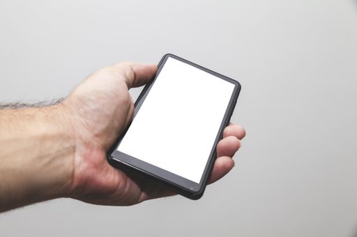 A closeup shot of a hand holding the phone with a white screen