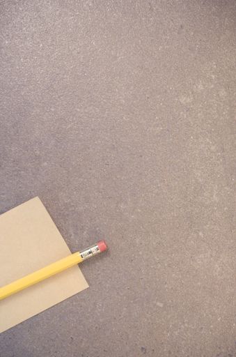 A top view closeup of a memo paper on a toned rough stone textured surface