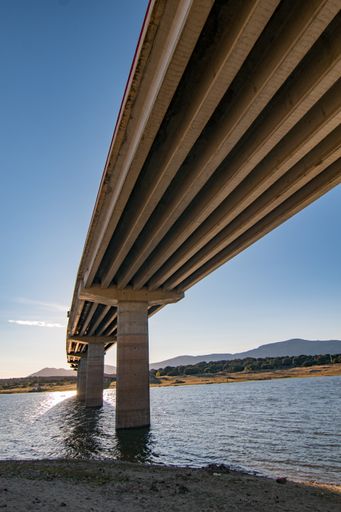 A low angle shot of a suspension bridge over a rive