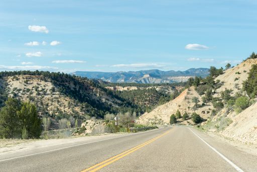 Lonely road between mountain ridges with some trees on each side of the road, somewhere in Utah towards north, United States
