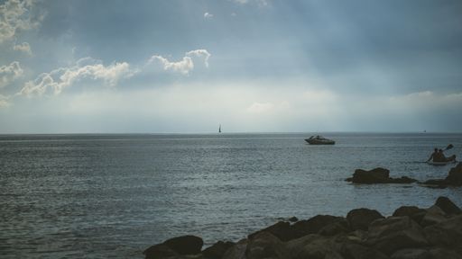 A majestic wavy sea under a dramatic heavy cloudscape with bright sun rays shining through clouds