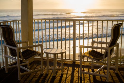 The two deck chairs and a small table in the balcony with a view to the beautiful sunset over the sea