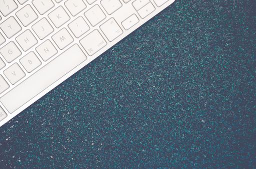 A top view of a computer keyboard on a stone textured surface with copy space