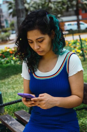 A vertical shot of a Hispanic young woman looking at her phone