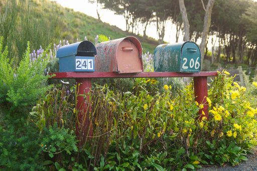 A view of three old and rustic postboxes on a red bank in New Zealand