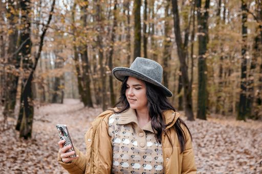 A closeup shot of a Caucasian woman in a sweater and hat into the woods during autumn