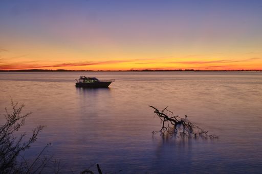 A sailing boat on the calm beautiful ocean with the breathtaking sunset in the background