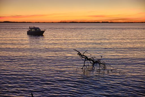 A sailing boat on the calm beautiful ocean with the breathtaking sunset in the background