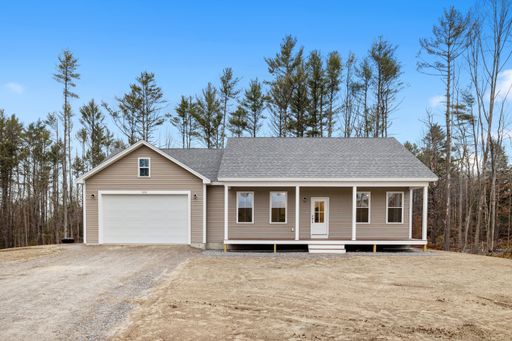 A front view of a contemporary and modern ranch-style house in the countryside with a gabled roofline and a front porch