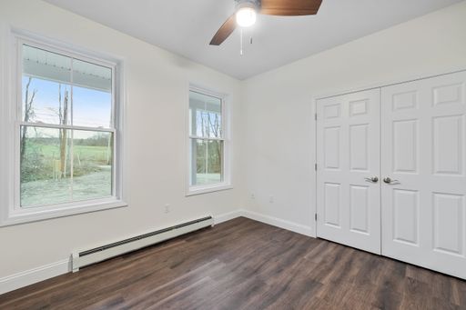 the interior of a room with a parquet floor, white walls and windows a double-sided door and a ceiling fan