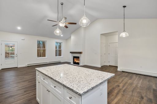 The interior of a house with white walls, a parquet floor, hanging lamps, and a fireplace