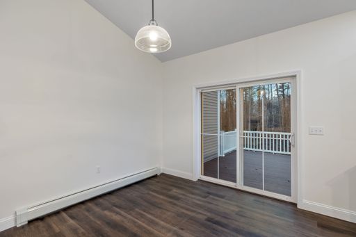 The interior of a room with white walls, a parquet floor, hanging lamp and a patio sliding door