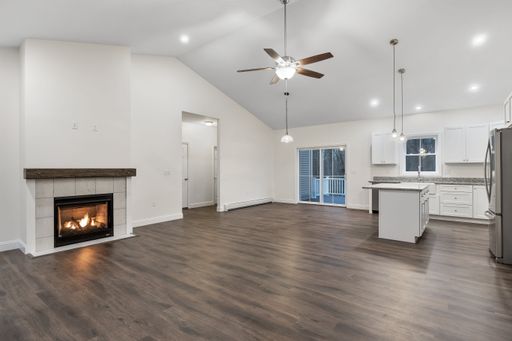 The interior of a house with white walls, a parquet floor, hanging lamps, and a fireplace