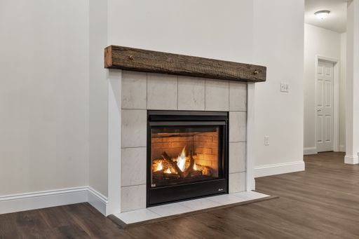 The interior of a house with white walls, a parquet floor, and a fireplace