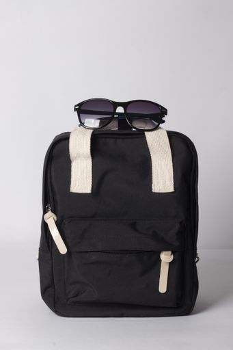 A vertical shot of a black travel backpack with sunglasses isolated on white background