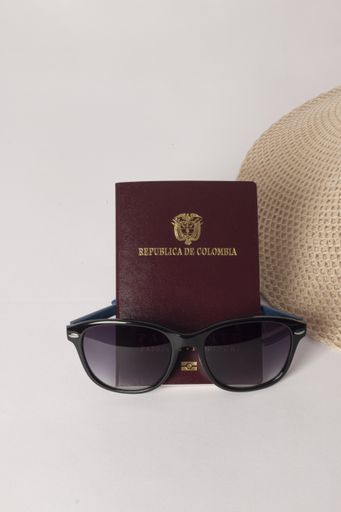 A vertical shot of sunglasses, passport, and hat isolated on white background - travel concept