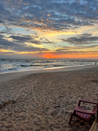 Cloudy sky over wavy sea and sandy beach at sunset