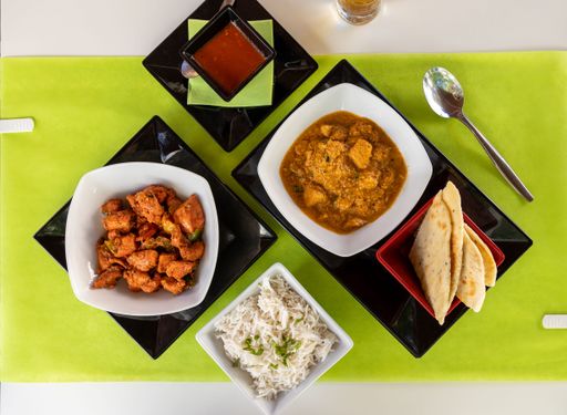 A top view of different Indian dishes on white table with green tablecloth