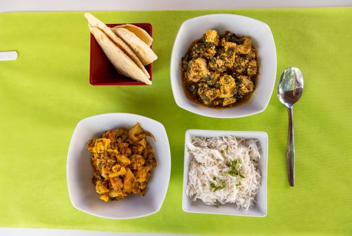 A top view of different Indian dishes on white table with green tablecloth