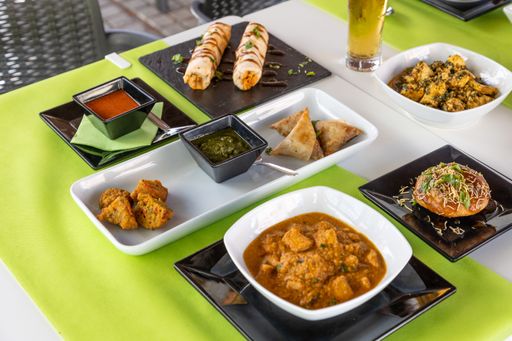 A closeup shot of different Indian dishes on white table with green tablecloth