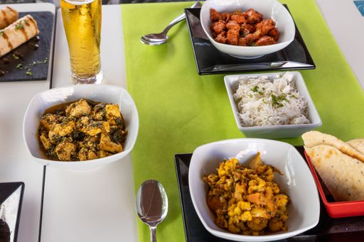 A closeup shot of different Indian dishes on white table with green tablecloth