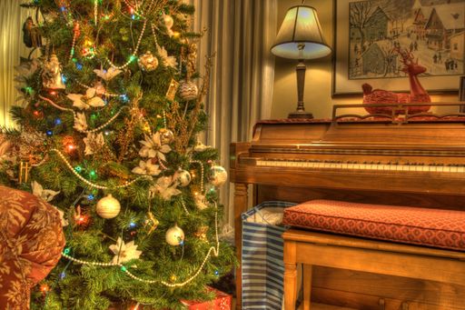 A living room with a brightly decorated Christmas tree next to a vintage piano