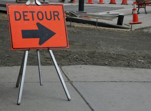 A closeup of an orange "DETOUR" sign with an arrow on a pavement on the construction area in Montpelier, Vermont