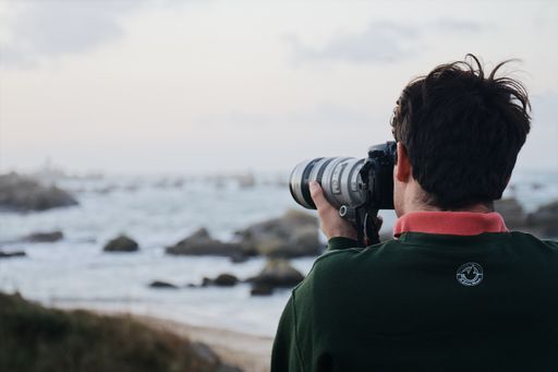 A photographer taking a picture of a rocky beach.